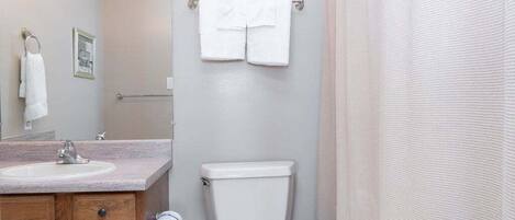 Une salle de bain équipée d’un lavabo, de toilettes et d’un porte-serviettes.