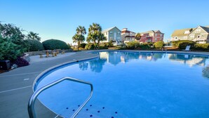 A swimming pool with a metal ladder, surrounded by a landscaped area with benches and palm trees. - Summer Palace B 2 Bedroom Duplex by RedAwning (Gulf Shores)
