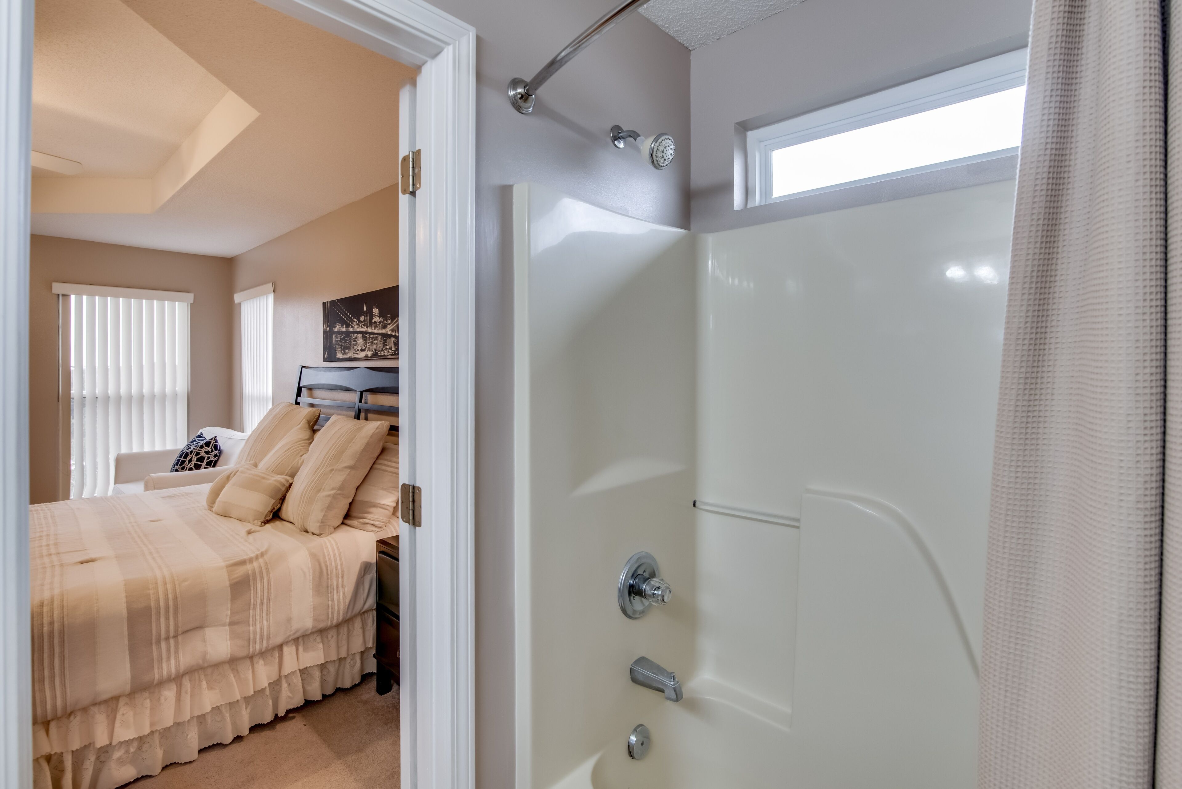 A bedroom with a bed, a shower, and a window.