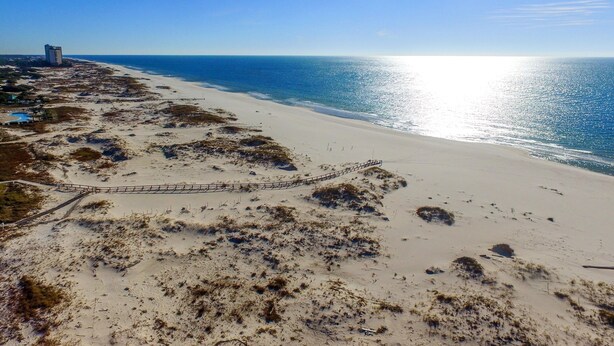 A beach with a sandy path leading to a building with a flat roof. - Summer Palace B 2 Bedroom Duplex by RedAwning (Gulf Shores)