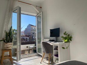 A balcony with a desk, chair, computer, and potted plants. - Apartment with 3 bedrooms, balcony, free Wi-Fi, a few minutes from 24 de Agosto (Porto)