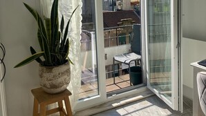 A room with a sliding glass door to an outdoor area, a potted plant on a stool, and a chair.