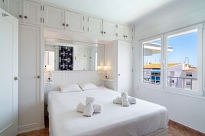 Une chambre d’hôtel avec un lit, un grand miroir, une fenêtre donnant sur un beau paysage et une armoire.