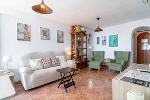 A living room with a sofa, armchairs, a coffee table, a cabinet, and artwork on the walls.