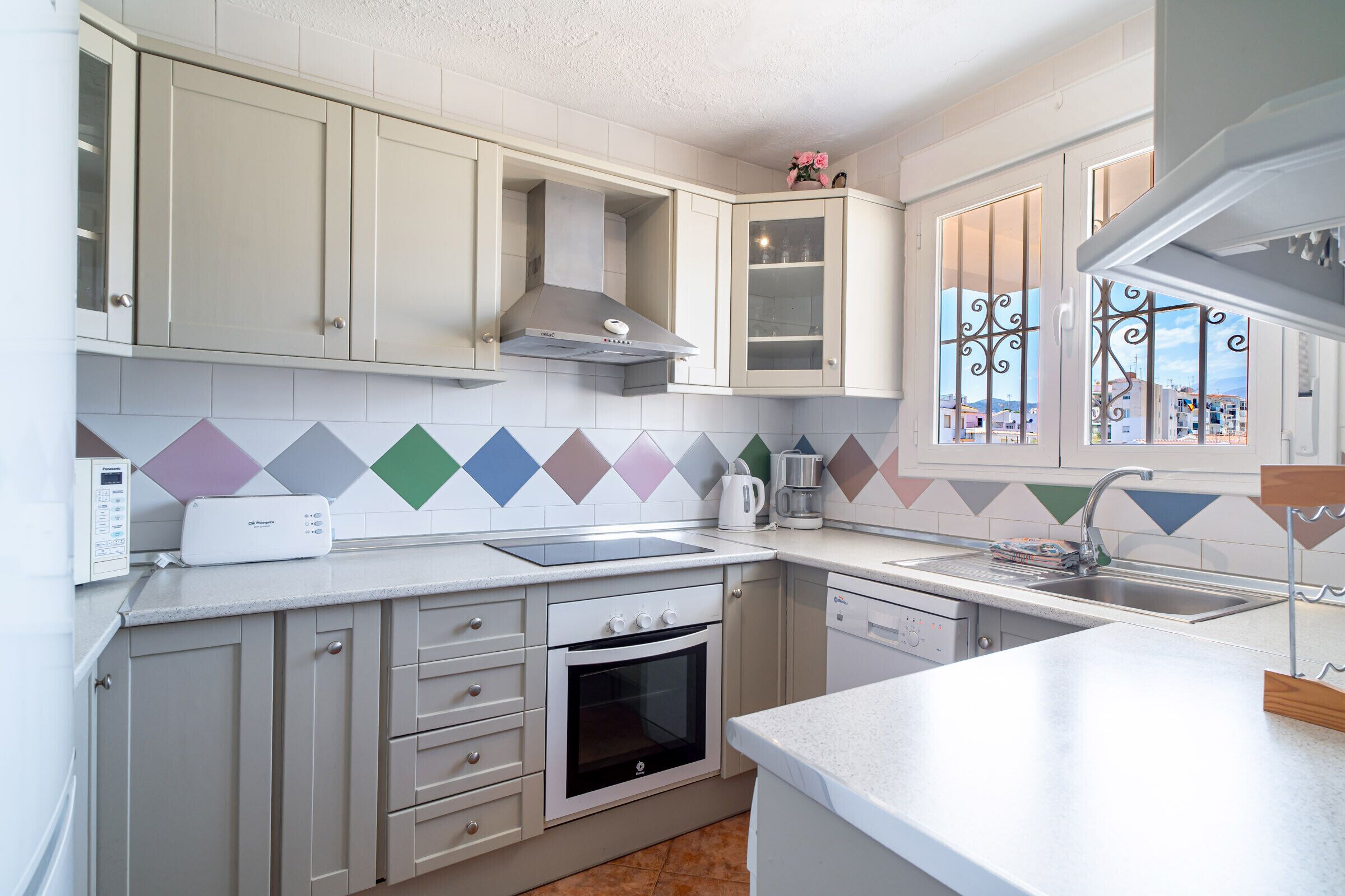 Une cuisine avec des meubles blancs, un four à micro-ondes, une cuisinière et un évier.