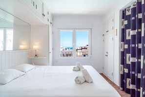 Une chambre d’hôtel avec un lit, une fenêtre donnant sur la ville, un miroir et un rideau.