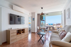 A living room with a TV, sofa, dining table, and chairs.