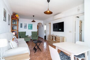 A living room with a sofa, chairs, a TV, and a dining table.