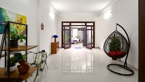 A hallway with a bicycle, a hanging chair, and a potted plant.