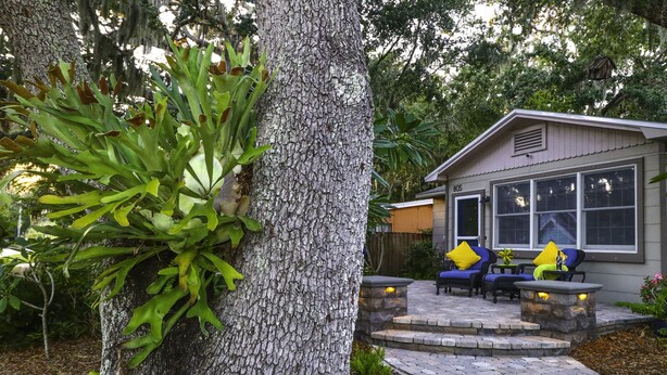 Une maison avec un chemin de pierre menant à un patio aménagé avec du mobilier d’extérieur.