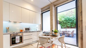 Uma cozinha moderna com armários brancos, micro-ondas e um espaço de jantar com cadeiras e mesa brancos.