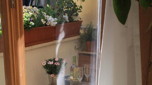 A glass door leading to a patio area with a wooden table, chairs, and potted plants. - house in the medieval district of Tivoli (Tivoli)