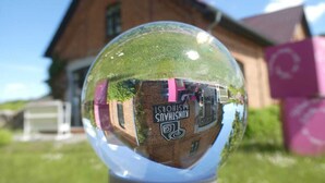 A clear glass sphere reflecting a building with the text "ISCHASCHAM" and an Instagram logo.