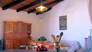 Una cocina con armarios de madera, una mesa de comedor y una lámpara colgante.