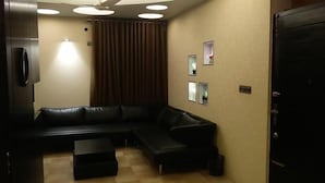 A modern living room with a sectional sofa, a small coffee table, and a ceiling fan. - Redwan's home (Dhaka)