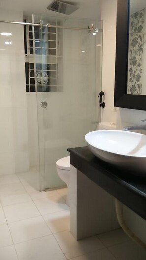 A modern bathroom with a glass-enclosed shower, a white toilet, and a large white sink with a black countertop. - Redwan's home (Dhaka)