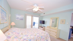 Une chambre à coucher comprenant un lit, une commode, un téléviseur et un ventilateur de plafond.