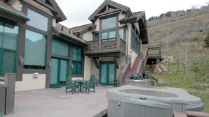 Une maison moderne à deux étages dotée d’une grande terrasse, d’un espace salon extérieur et d’un jacuzzi.