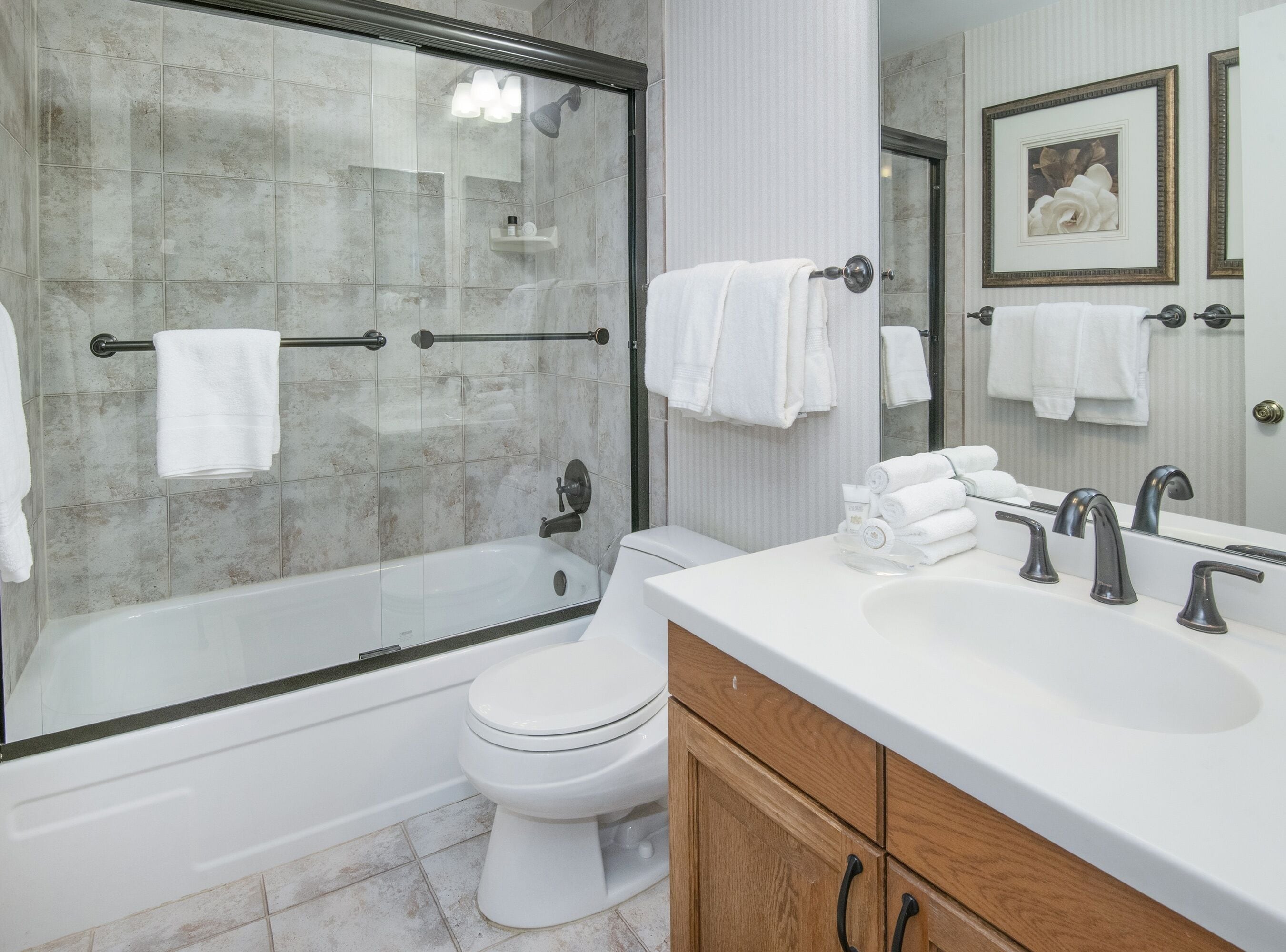 Een moderne badkamer met een douchecabine van glas, een wit toilet en een wastafelmeubel met een wastafel en meerdere kraanwerk.