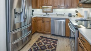 A modern kitchen with stainless steel appliances, wooden cabinets, and a built-in dishwasher.