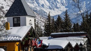 A mountain lodge with a snow-covered roof, a bell tower, and flags.