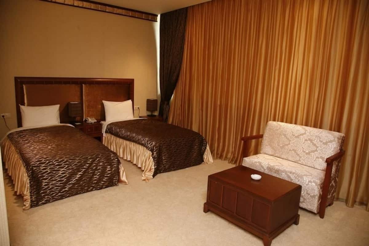 A hotel room with two beds, a sofa, and a small wooden table.