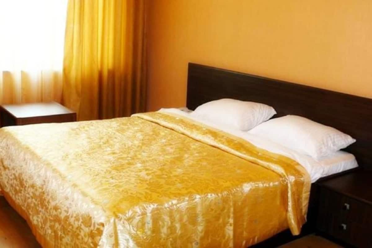 A hotel room with a bed, a nightstand, and a window with curtains.