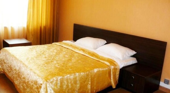A hotel room with a bed, a nightstand, and a window with curtains.