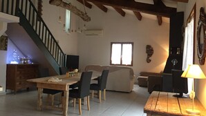 Un'ampia zona giorno con tavolo da pranzo in legno, sedie, divano e una scala.