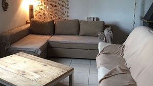 Un soggiorno con una poltrona, un tavolino in legno e un'opera decorativa a parete.