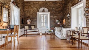 A rustic room with stone walls, wooden furniture, a white door, and a wooden ceiling.