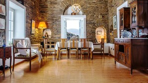 A rustic room with stone walls, a wooden dining table, and a view through an open door.