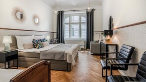 A modern hotel room with a large bed, two bedside tables, a chair, and a small table with a lamp. - PRG Trendy Central APT by Michal&Friends (Prague)