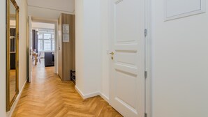 A hallway with a wooden floor, white walls, and a closed door with a gold handle. - PRG Trendy Central APT by Michal&Friends (Prague)