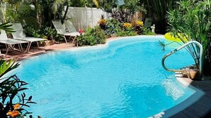 A swimming pool surrounded by lush greenery and palm trees.