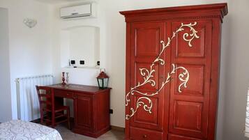A bedroom with a bed, a wooden desk, a red wardrobe, and a radiator.