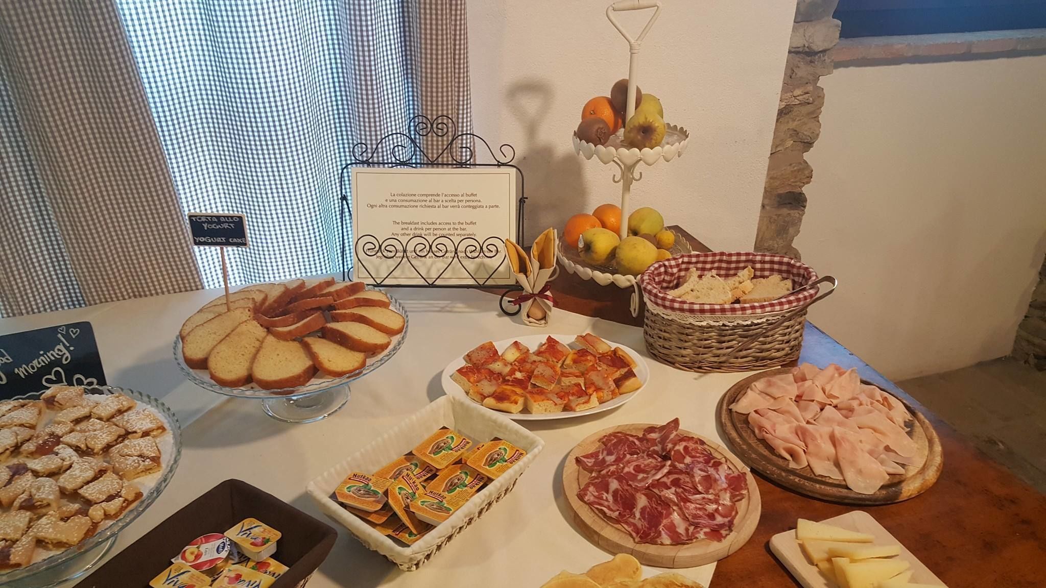 Una mesa de buffet con diversos alimentos, incluyendo un pastel, pastelería, queso y carnes.
