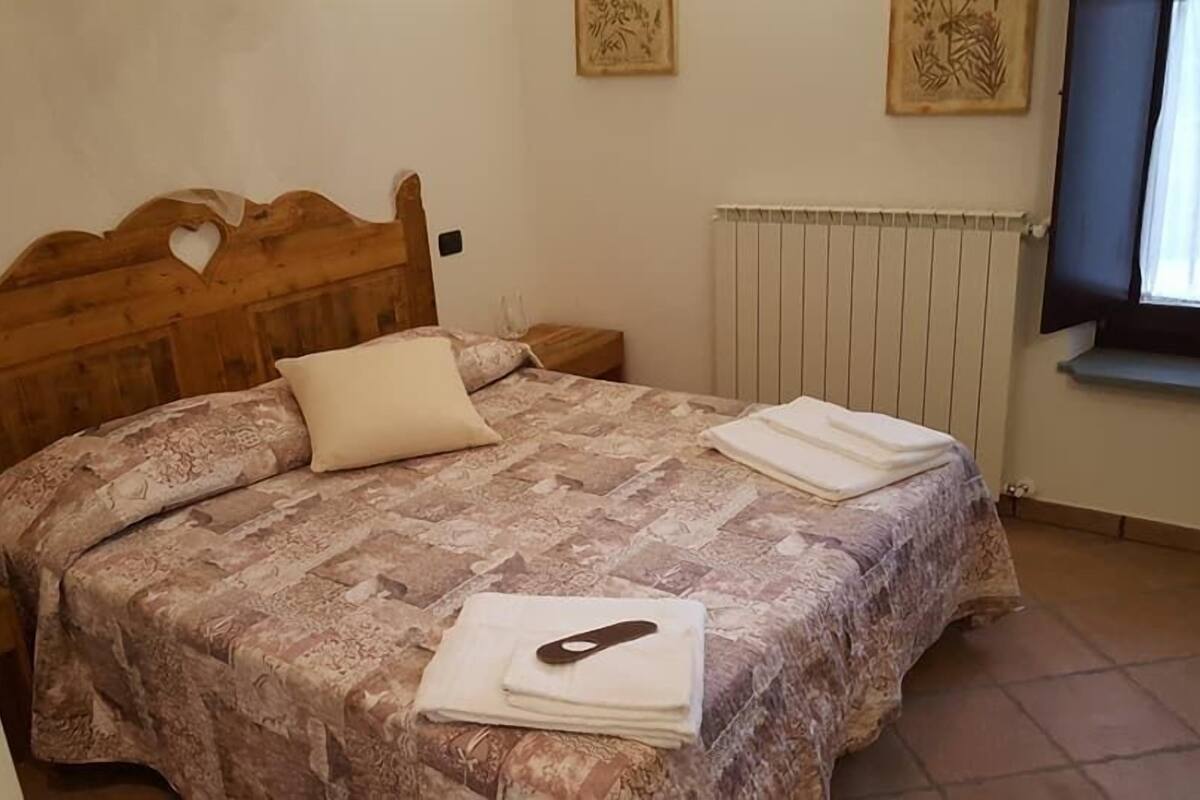 Un dormitorio con cabecera de madera, colcha estampada, almohada y toalla doblada en la cama.