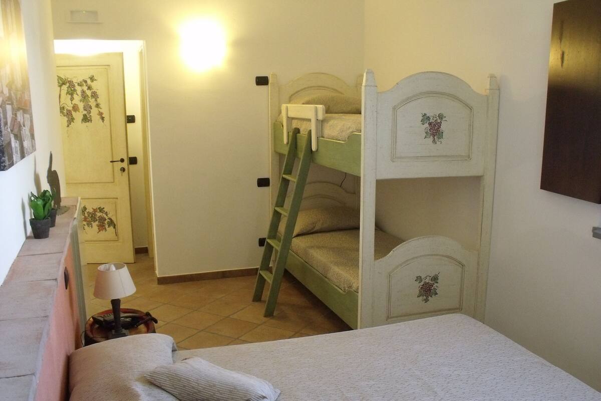 Un dormitorio con literas, una mesita de noche con lámpara y una puerta decorada con motivos florales.