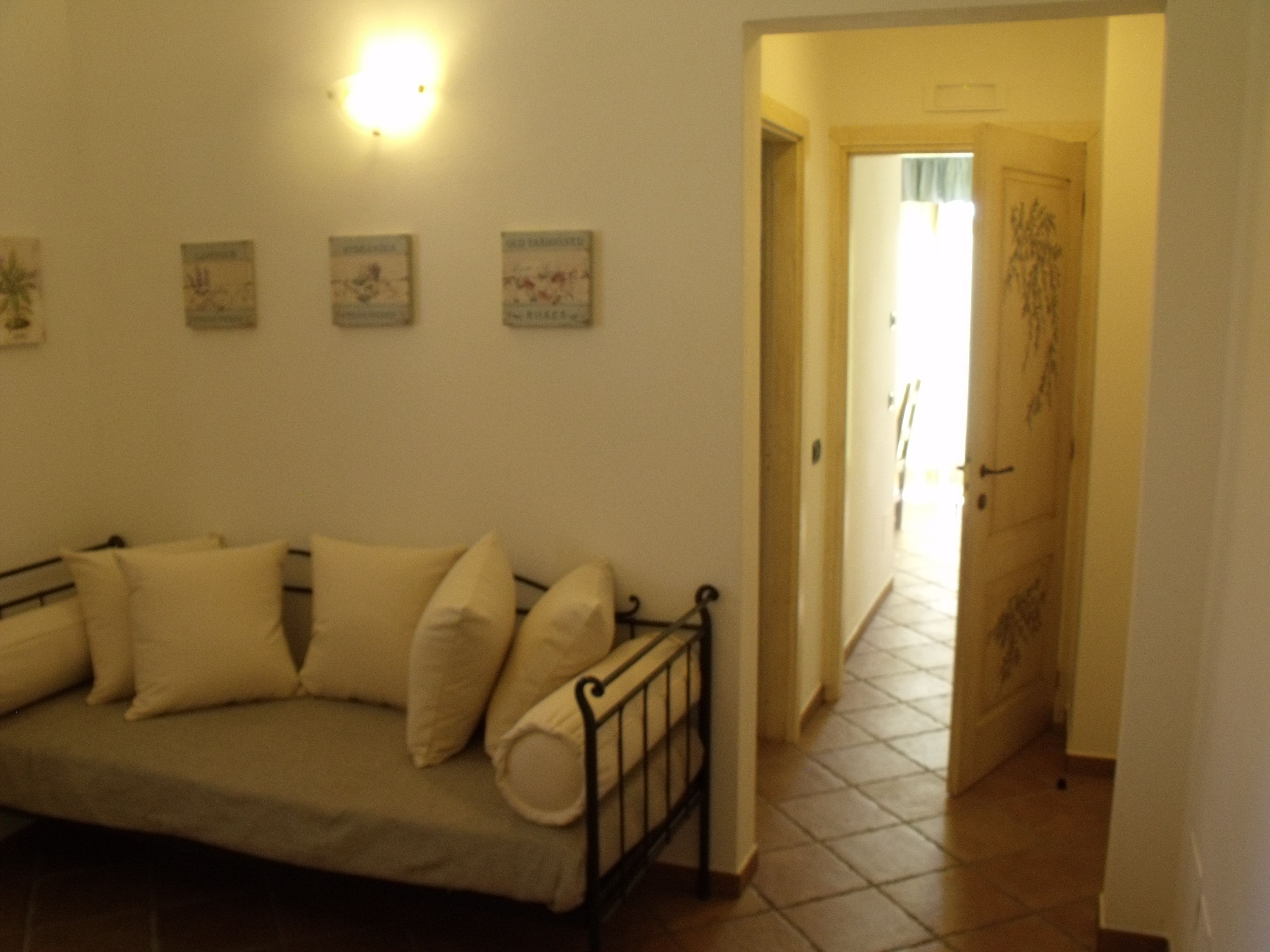 A room with a beige sofa, a wall-mounted light fixture, and a door leading to another room.