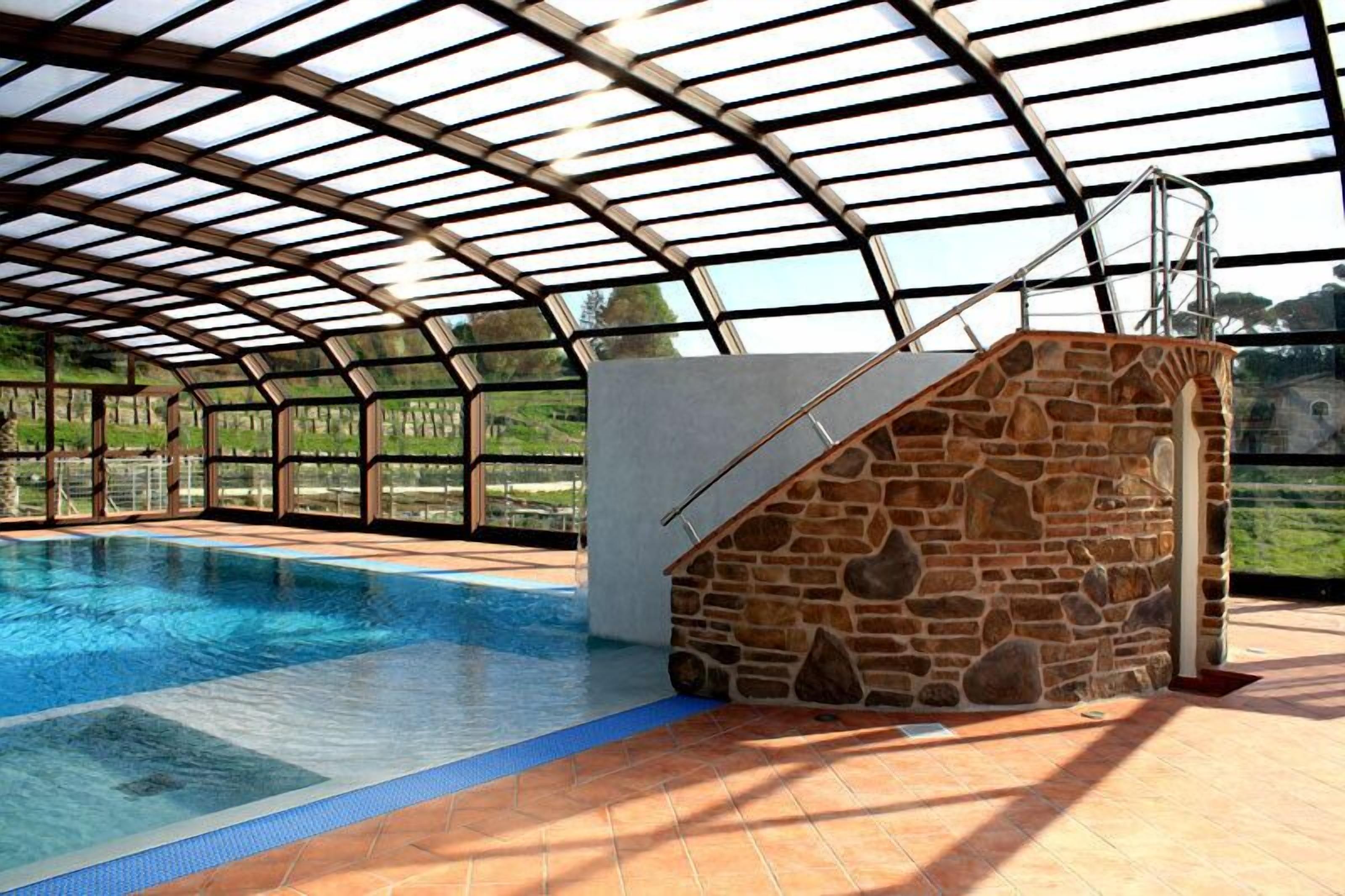 Una piscina interior con pared de piedra y escalera metálica que sube a una plataforma de observación.