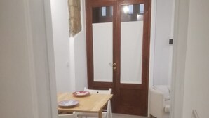 A small dining area with a wooden table and chairs, a white chair, and a cabinet with glass doors.