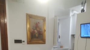 A small, cozy room with a chair, a table with a pumpkin, a framed picture, a television, and a cabinet.