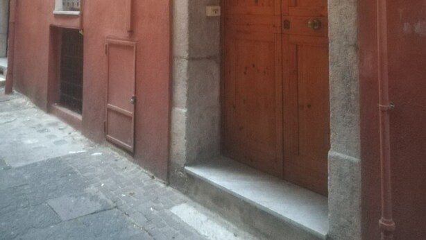 A red building with a wooden double door and a small window with bars.