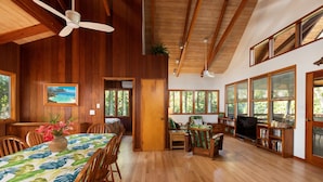 Quarto espaçoso com piso de madeira, área de refeições com mesa e cadeiras, um sofá e uma estante de livros.