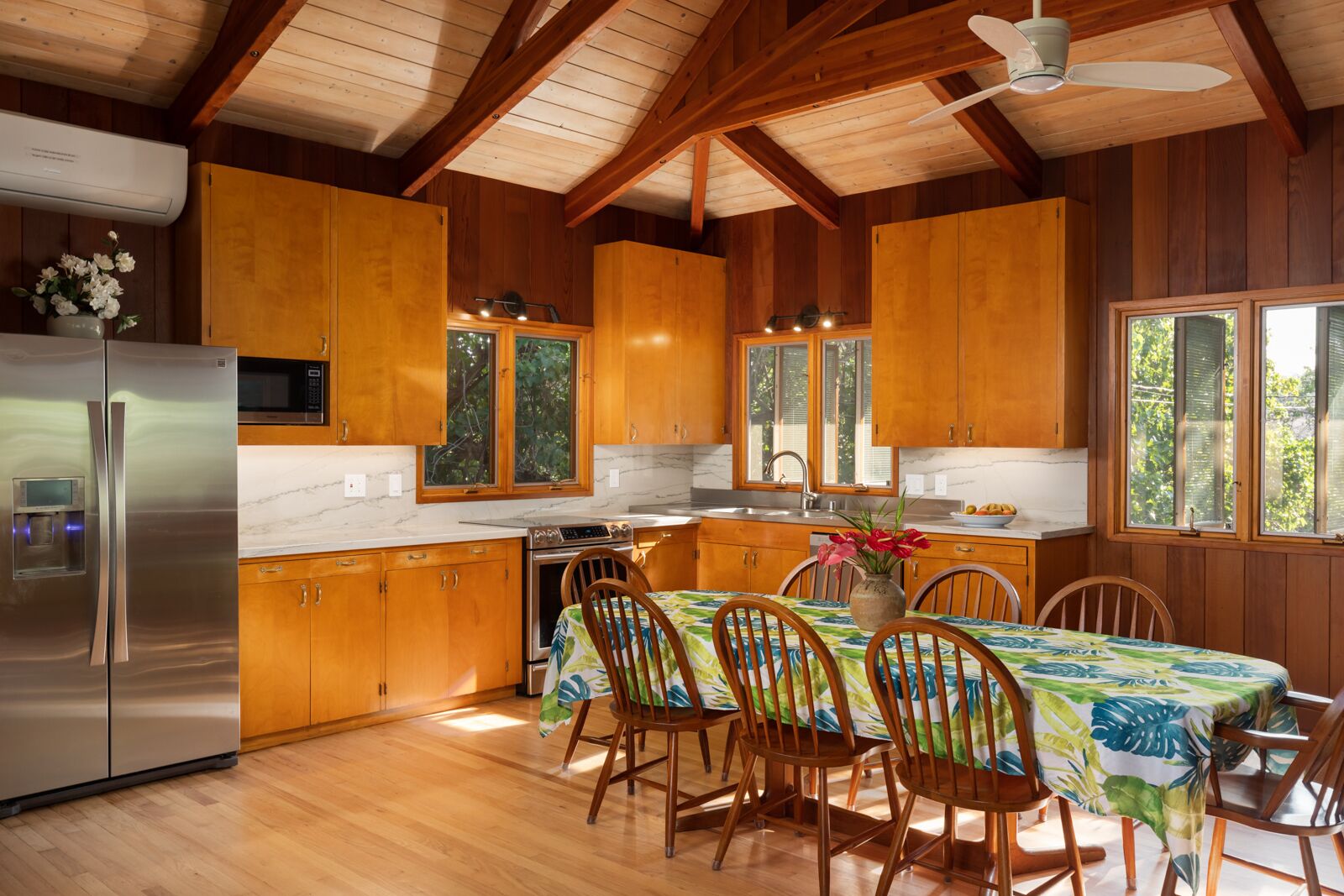 A kitchen with wooden cabinets, a stainless steel refrigerator, a microwave, and a dining area with a table and chairs.