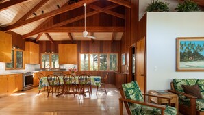 Uma cozinha ampla com armários de madeira, um espaço de jantar com mesa e cadeiras, e uma sala de estar com sofá e poltronas.