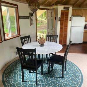 A round dining table with four chairs, a globe centerpiece, and a patterned rug. - Retreat to wine country (Amity)