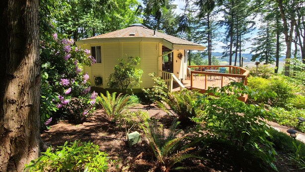A yellow cabin with a deck, surrounded by dense forest and a clear view of the mountains. - Retreat to wine country (Amity)