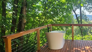 A wooden deck with a white outdoor seating area, surrounded by trees and a view of distant hills. - Retreat to wine country (Amity)